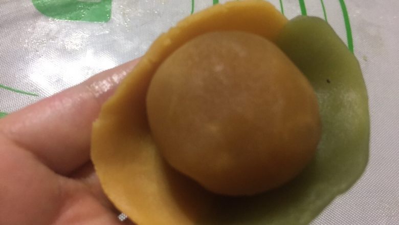 双色桃山皮月饼,桃山皮捏成厚薄均匀的薄片,把核桃酸乳酪馅放在桃山皮中间。