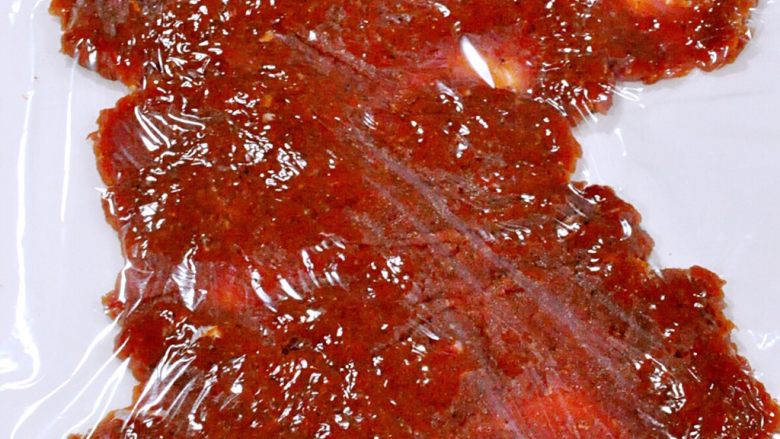 蜜汁黑椒肉脯,半小时后取出肉末,取1/4平铺在裁好的油纸上,肉末上面盖上保鲜膜。