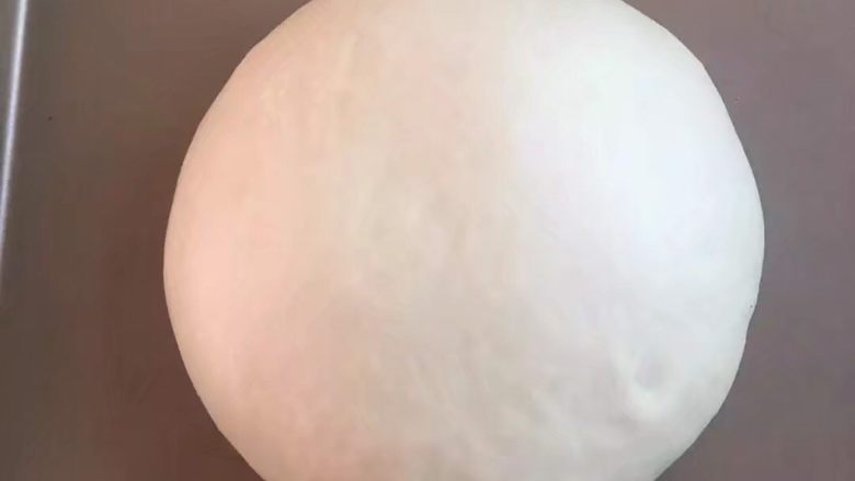 网红乳酪包,发酵好的面团取出。揉圆放在金盘里,在烤箱里进行二次发酵