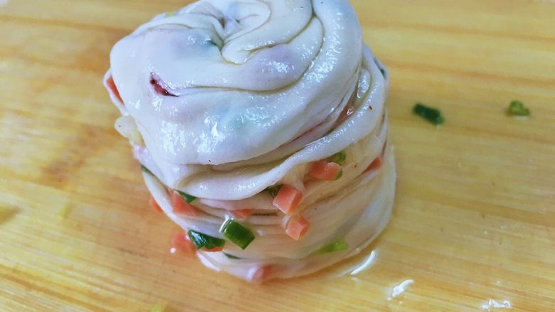 手撕火腿葱花饼,将卷好的长条从一头开始卷成一个面团,边卷边拉紧【油比较多的话这里就不好控制了】,最后的一头塞进面团底部。
