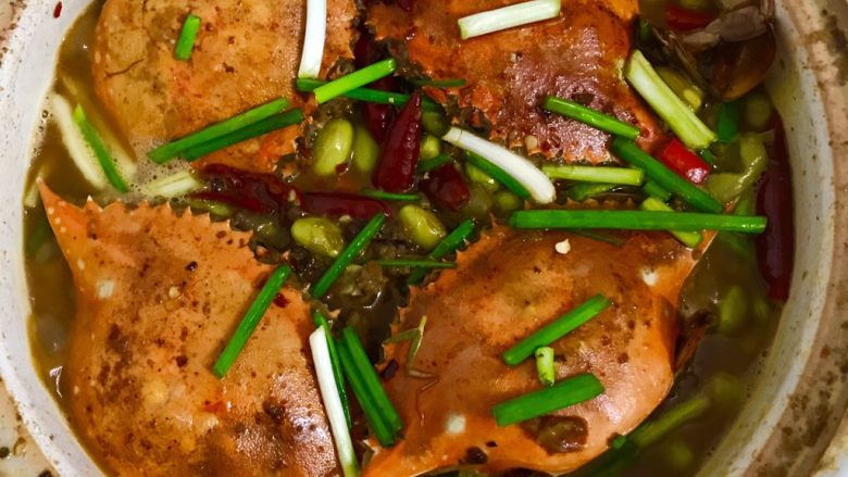 蟹煲,锅里另起油放入洋葱辣椒炒香
，到入炸好的蟹来回翻炒倒入老抽炒香捞出。砂锅里倒进切好的芹菜段毛豆再把炒好的蟹覆盖上加水烧干撒葱即可
