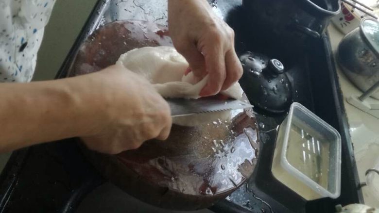 清汤猪肚,这时候从开水里把猪肚捞上来,放在砧板上切开一道口子