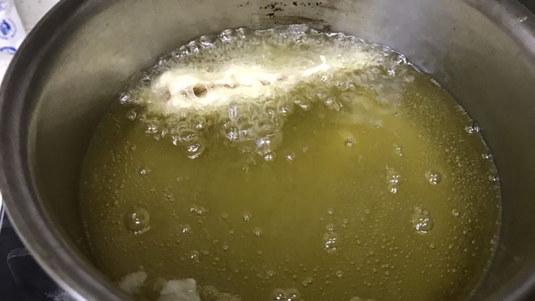 油炸穿条鱼,小鱼可以迅速冒泡,炸飘起来,说明油温可以了,将火调至中小火。