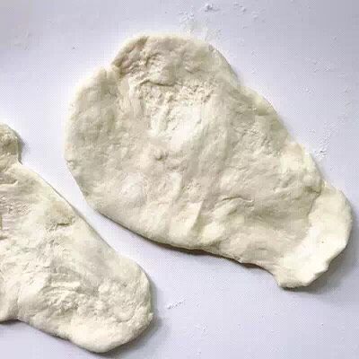 简易手作烤饼,将面团分成四等份,工作台上撒上低筋粉,将面团压薄展开,注意不要太薄。