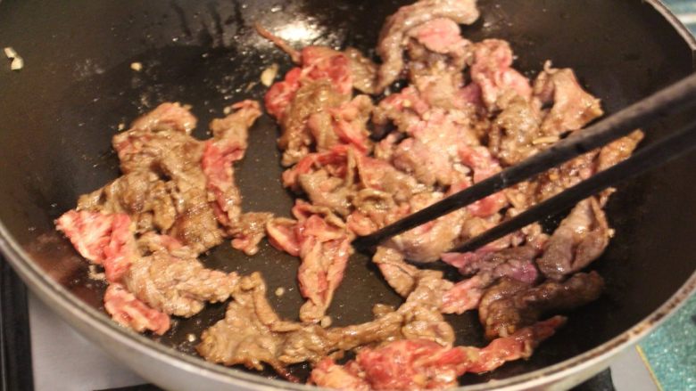 橙汁芝麻牛肉,炒锅热锅后,加入两大匙油。油热后,分次放入牛肉片,入锅后迅速用筷子拨散,以免牛肉黏成一团。