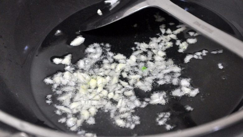 豇豆肉末,将油锅热至6成热,放入蒜末,快速翻炒。