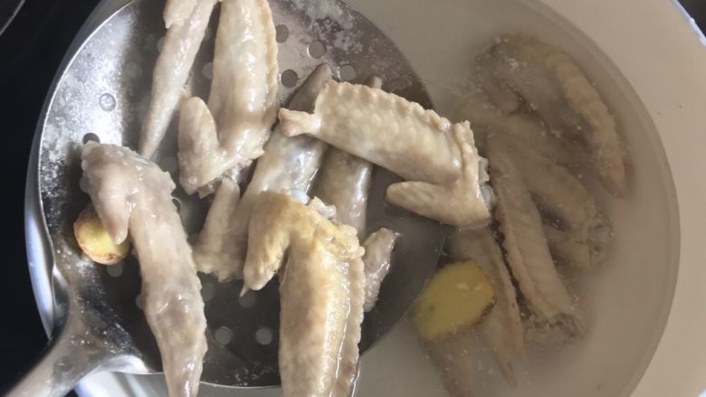 独家香辣鸡翅尖,关火,将鸡翅尖捞出放在准备好的清水里洗去残留的浮末,如下图👇