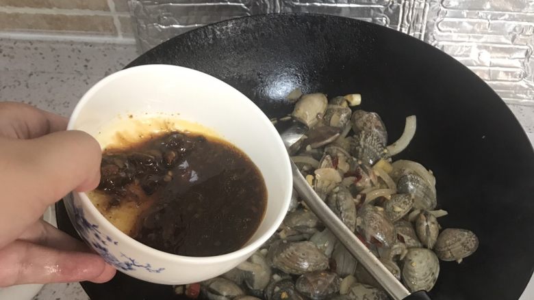 爆炒花甲,倒入调好的酱汁,翻炒