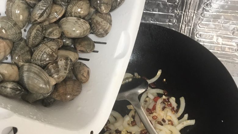 爆炒花甲,花甲沥干水倒入锅内,翻炒