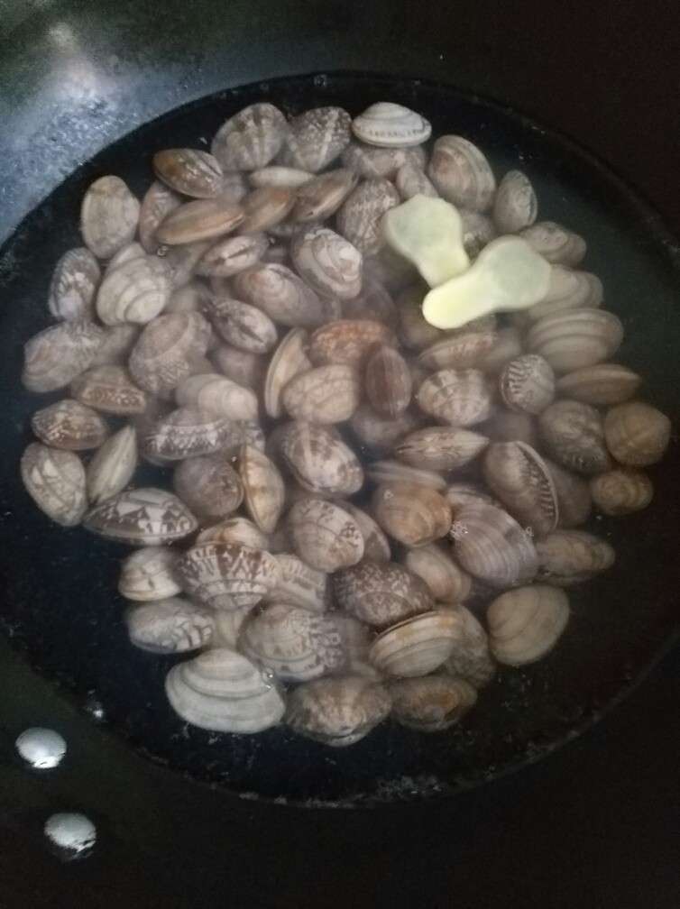 香辣爆炒花甲,烧一锅开水,水开后倒入花甲,放入姜片,盖锅焖煮,这会人不能离开,要不然会溢锅