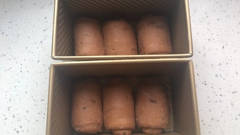 酸奶巧克力豆吐司,翻面,自上往下卷起,排入吐司盒中。卷2.5圈为宜