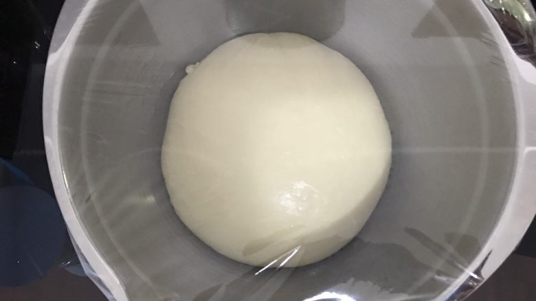 养乐多奶油小面包,取出面团,放进干净盆里,盖上保鲜膜放在温暖处进行一次发酵。夏天温度高,直接室温发酵即可。