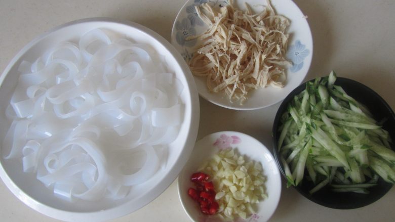 鸡丝凉皮,将浸泡好的凉皮切成条放入盘中,鸡脯肉手撕成丝, <a style='color:red;display:inline-block;' href='/shicai/ 54'>黄瓜</a>也切成丝;