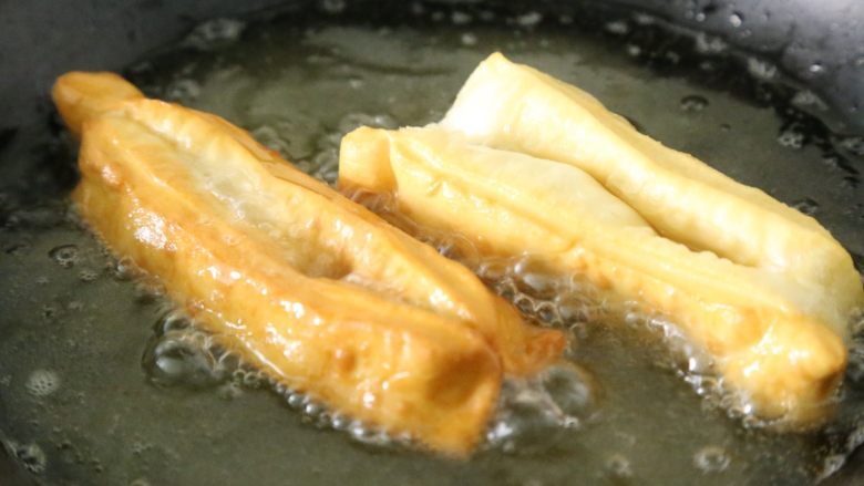 武汉小吃 糯米包油条,油锅烧热,将造型好的油条放入油锅浸炸,直至油条蓬松成金黄色,捞出沥干油备用。