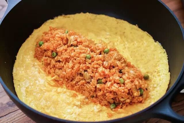 治愈系蛋包饭,关火,米饭放在蛋皮中间,翻起蛋皮的一边将米饭包住,把锅倾斜后翻扣在盘中