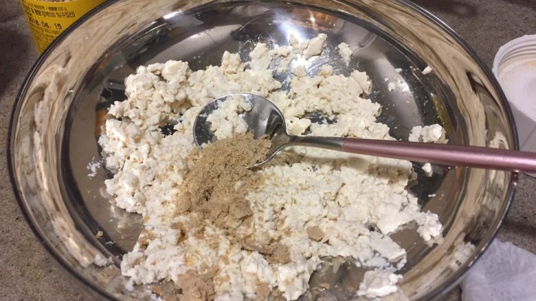 日式蔬菜拌豆腐,把磨好的芝麻粉加入碾碎的豆腐里,拌匀。