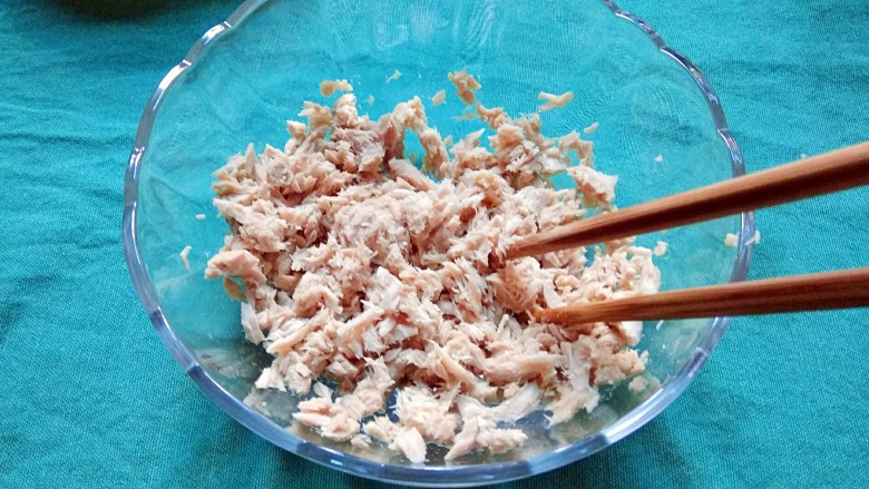 金枪鱼沙拉,把金枪鱼肉倒进一个大的沙拉碗,用筷子打散,放在一旁备用。