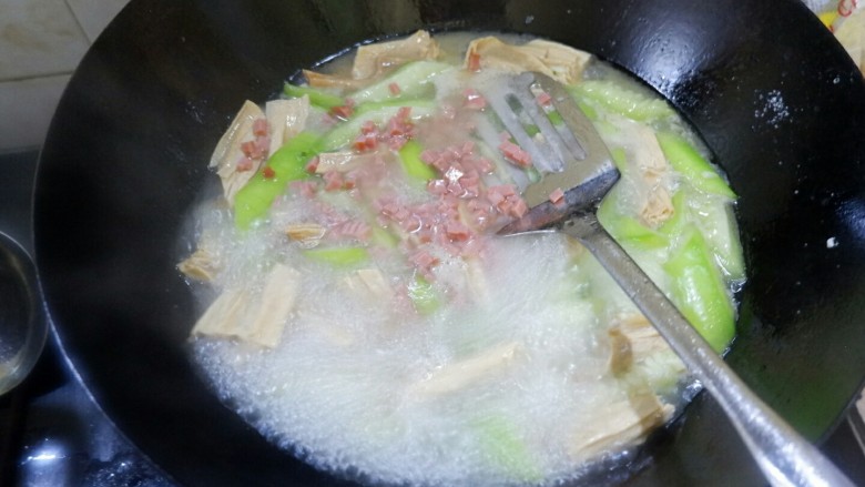 一鸡两吃之一汤一菜,滚开以后把火腿丁扔进去,放盐调味儿,出锅。丝瓜嫩,易熟。