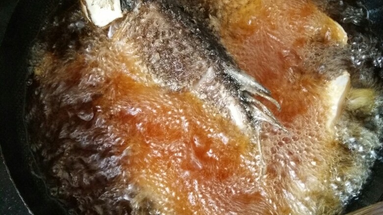 万州烤鱼,锅内烧油,油热九成下鱼,鱼皮朝上,不然容易粘锅,炸制金黄捞出