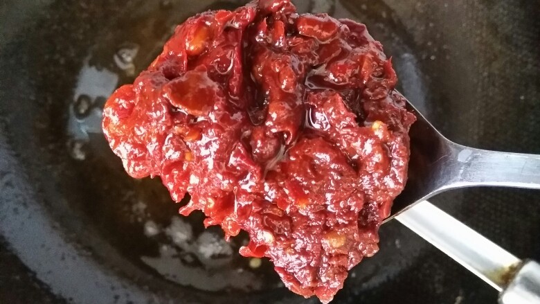 万州烤鱼,锅内放少许油,油烧热放一勺红油豆瓣,炒出红油