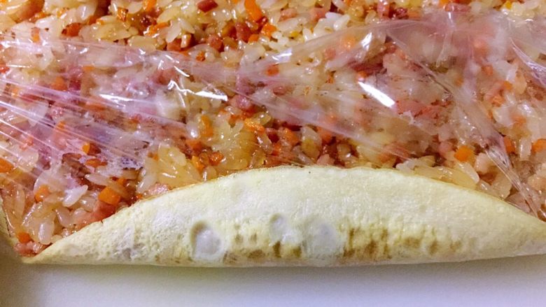 培根胡萝卜鸡蛋卷饭团,掀起保鲜膜一边,开始卷饭团