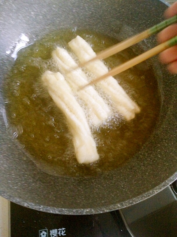 家庭自制油条,用筷子翻拨,使其受热均匀。