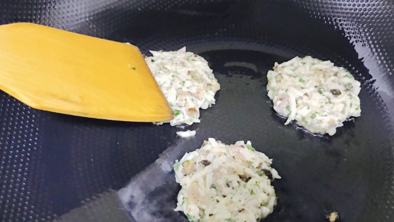 香煎藕饼,锅中倒入花生油,热锅凉油,将莲藕球放入锅中,然后用锅铲轻轻地压扁它们,慢慢地调整形状,尽量压成一个规整的圆形