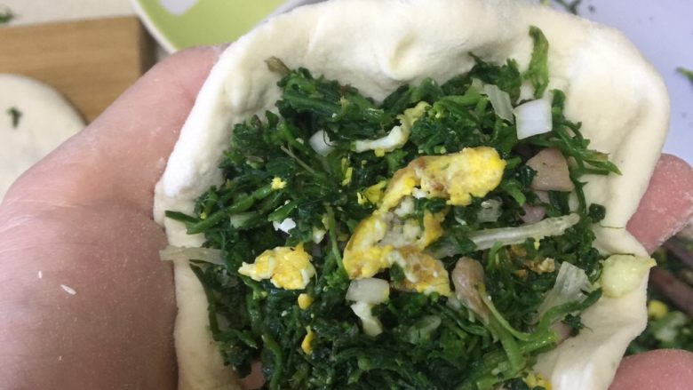 荠菜馅饼,把面饼放手里,菜可以多放些,捏着面边开始转着圈的捏在一起,然后在擀薄。