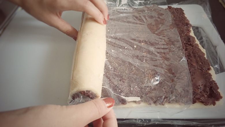 赖爸芸豆卷,抻住保鲜膜两侧,借助保鲜膜卷起