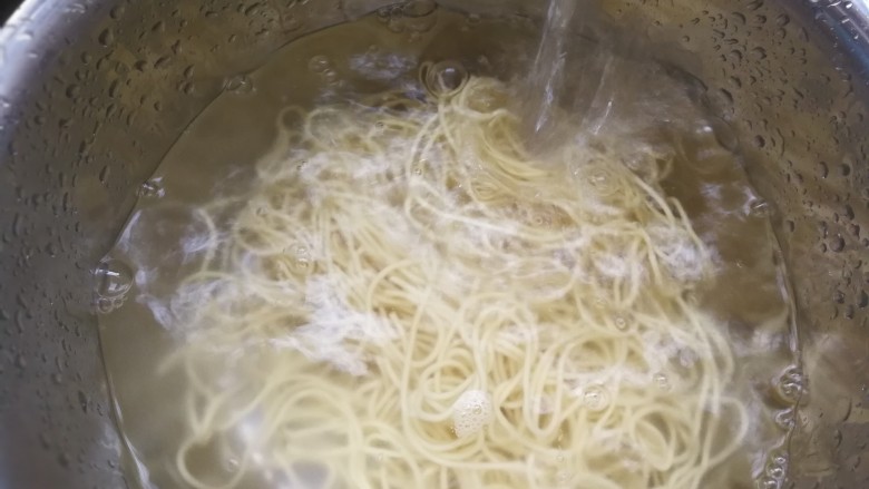 椒香葱油面,将面直接倒进漏篮,将热水全部滤出,动作要连贯迅速,不要拖拖拉拉,当然也要注意别烫着。面入盆用冷水冲,边冲边换掉里面的水。