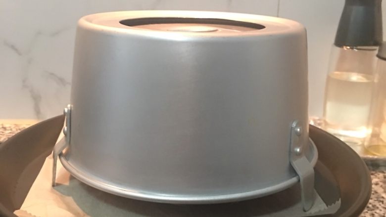 紅玉奶茶戚風蛋糕,将蛋糕从烤箱取出后,先将模具提起落下敲桌面1下后马上倒扣。