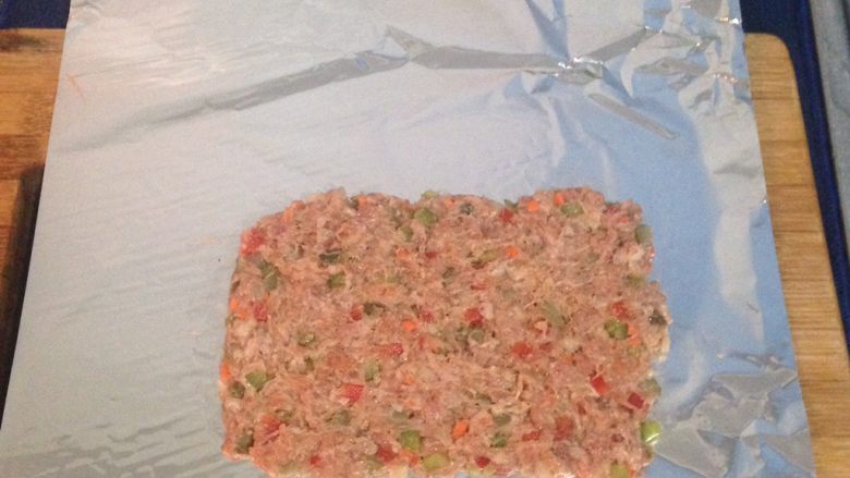 西班牙肉卷 Embotido,鋁箔紙舖平,再舖上一層混勻調好料的絞肉(長度請先測量您的蒸鍋直徑)。