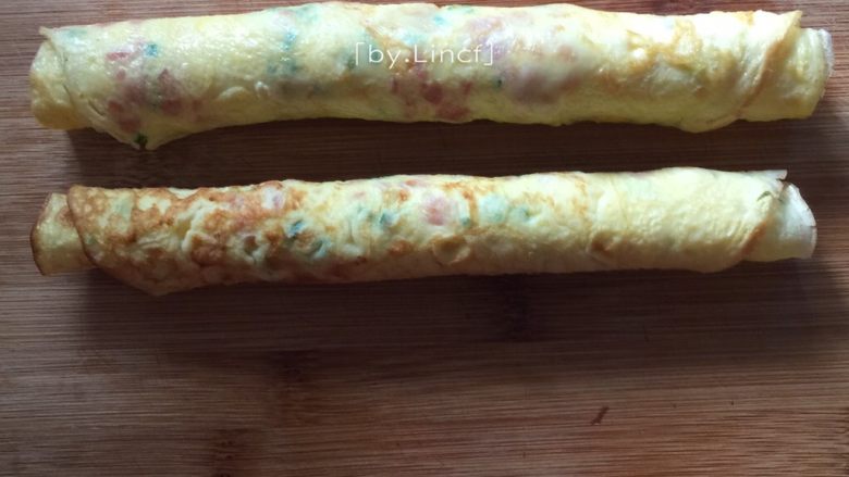 火腿蒜香鸡蛋卷,趁有温度时轻轻卷成卷,尽量卷紧一点哦,不然易松散开来