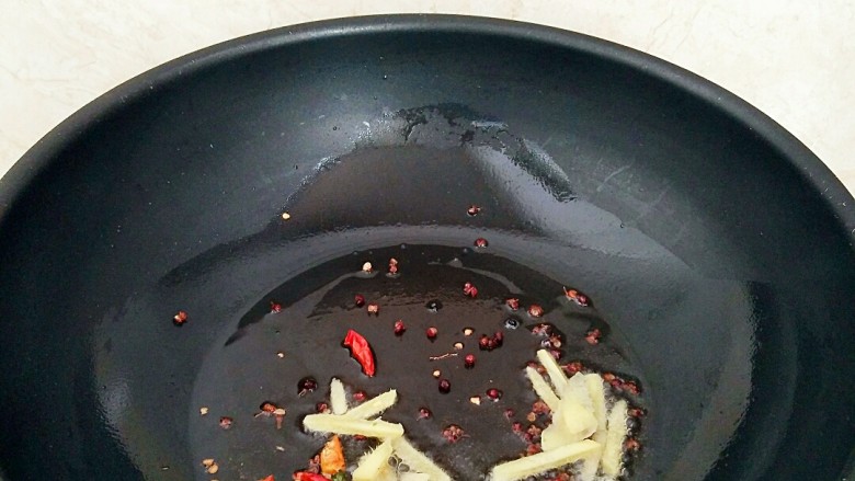 香辣蚕蛹,锅中放油烧热,放入花椒粒,姜,辣椒呛出香味。