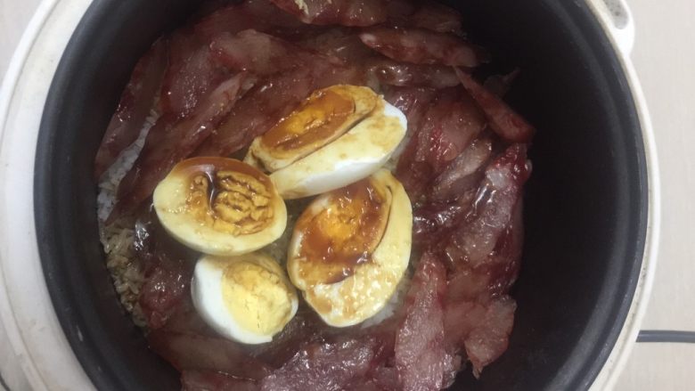 电饭锅煲仔饭,然后把切好的腊肠,鸡蛋咸鸭蛋放进去,淋上调好的汁,盖上盖子焖五分钟即可出锅