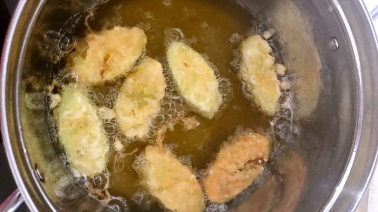 酥炸茄盒,锅内加入700ml大豆油,烧5分热的时候放入裹好蛋液的茄片,温火炸制