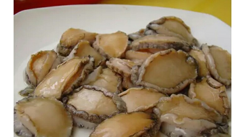 家常鲍鱼捞饭,小心的用刀子将鲍鱼与鲍壳分开,去除内脏后清洗干净。