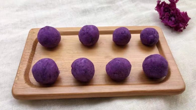紫薯南瓜椰蓉球,将紫薯面团搓成长条,用刀切小块,再搓成大小一致的小圆球。