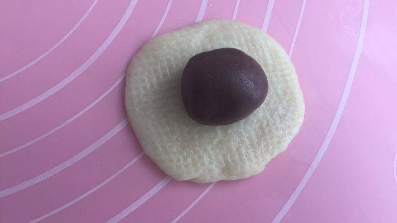 可可蛋黄酥,油皮擀成圆皮,把酥皮放进去。包紧收口。