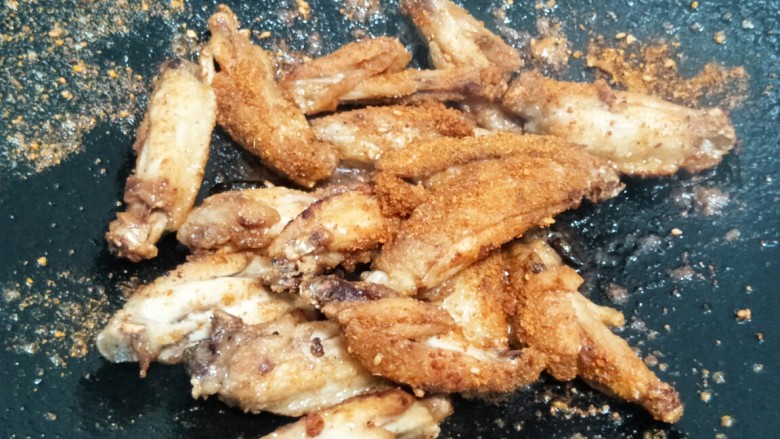 酥香炸鸡翅,将多余的油倒出,加适量食盐,再加烤肉粉,翻炒