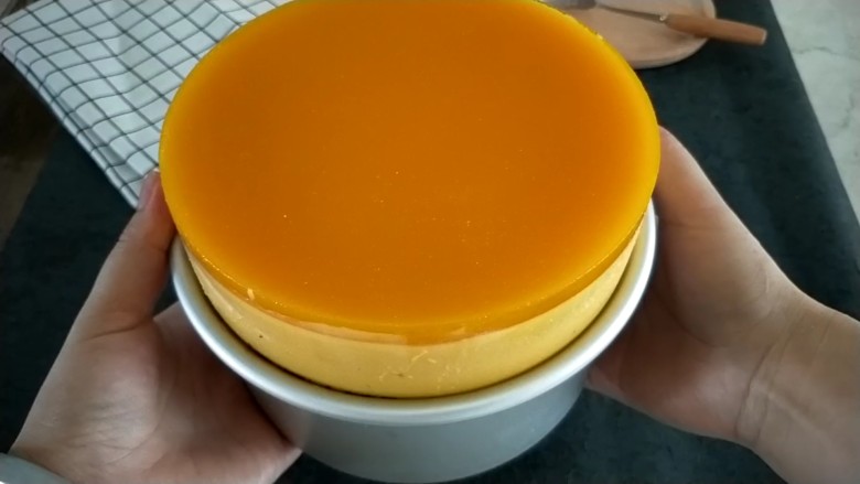 南瓜酸奶慕斯,冷藏好的慕斯,用热帕子捂捂或电吹风吹模具边缘1分钟,模具底放一个杯子,双手扶着模具边缘往下按,就轻松脱模了