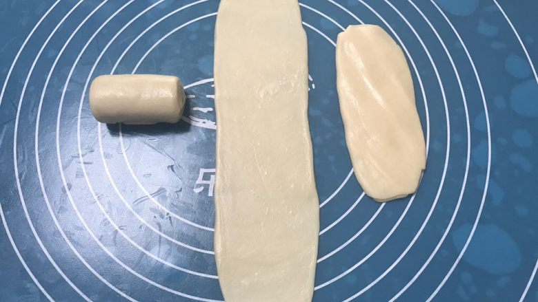 榨菜鲜肉月饼,再次取第一个卷好的面团,用手掌摁一下然后擀成长舌状,比之前擀的要窄一些,由上至下卷起