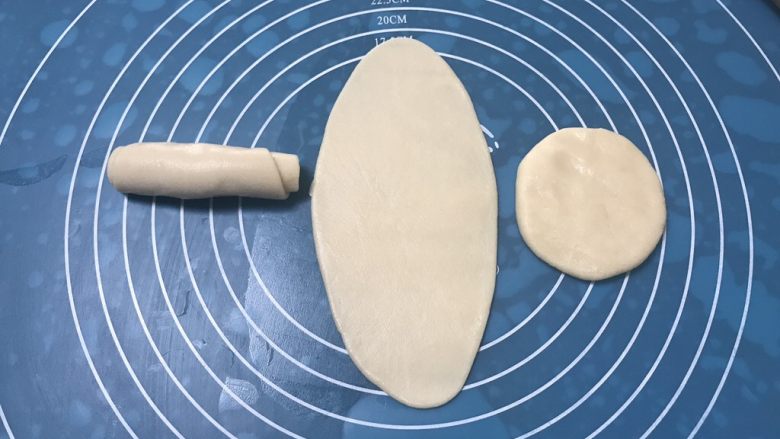 榨菜鲜肉月饼,取第一个包好的面团用手掌摁一下,然后用擀面杖擀成长舌状,要从中间分别往上下擀开,由上至下卷起,保鲜膜盖好,