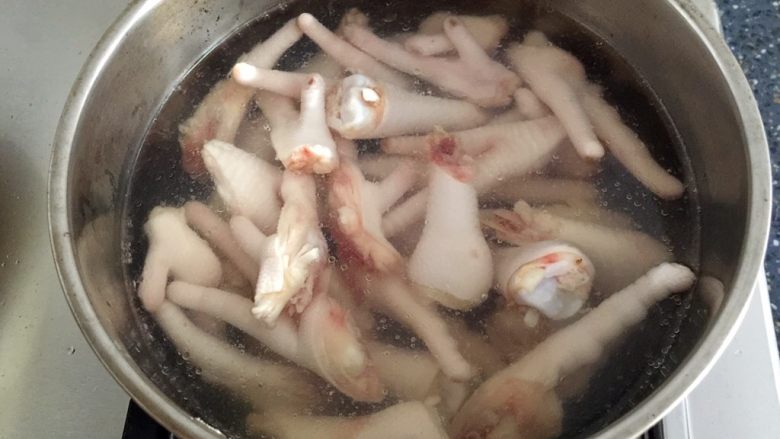 酱醋泡鸡爪,锅里放入清水和几片姜片烧开,放入切好的鸡脚。