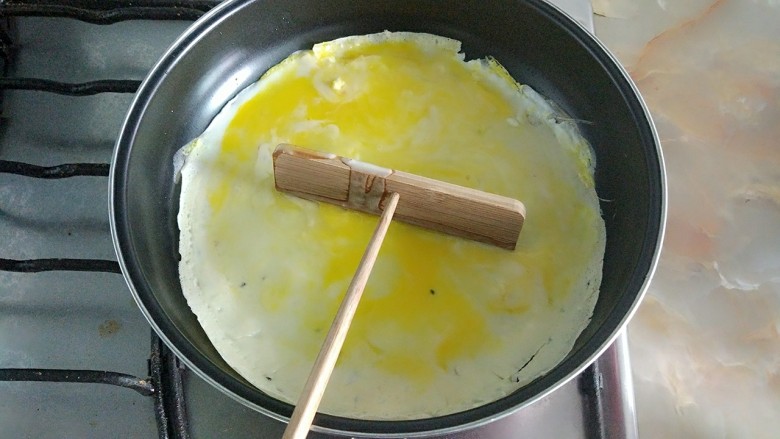 家庭版简易鸡蛋卷饼，双蛋青菜营养版,用竹蜻蜓把鸡蛋铺匀。