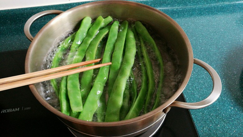 五花肉炒刀豆木耳,锅里水开后先放入一小勺食盐,然后放刀豆焯水。放入食盐焯水的刀豆颜色会更绿。