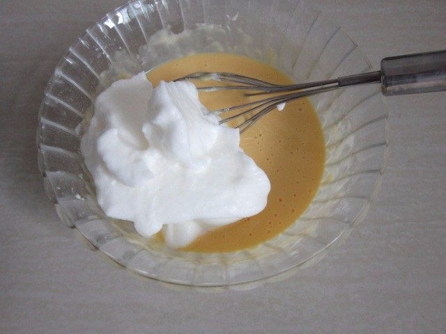 蔓越莓蛋糕卷,取三分之一蛋白糊,倒进蛋黄糊中,用翻拌的手法混合均匀。