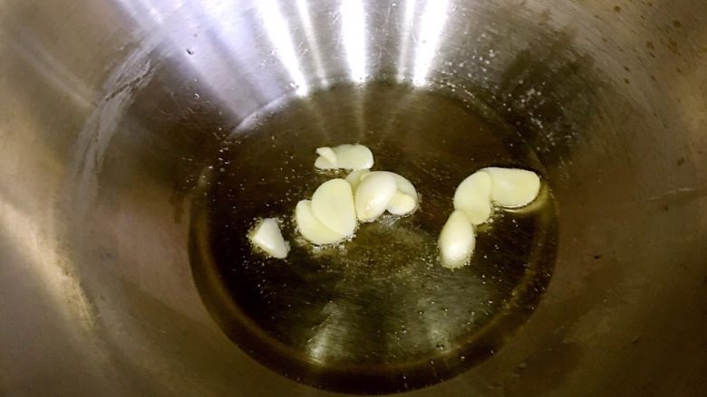 酱香茄子,热锅以后倒入油,烧至7成热,放入蒜,翻炒出香味。