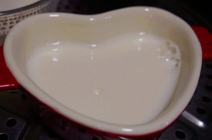 蜜豆桂花双皮奶,把拌好的牛奶缓缓倒入原来的碗中,使原来的奶皮浮起,盖上盖子,放到火上文火慢蒸15分钟