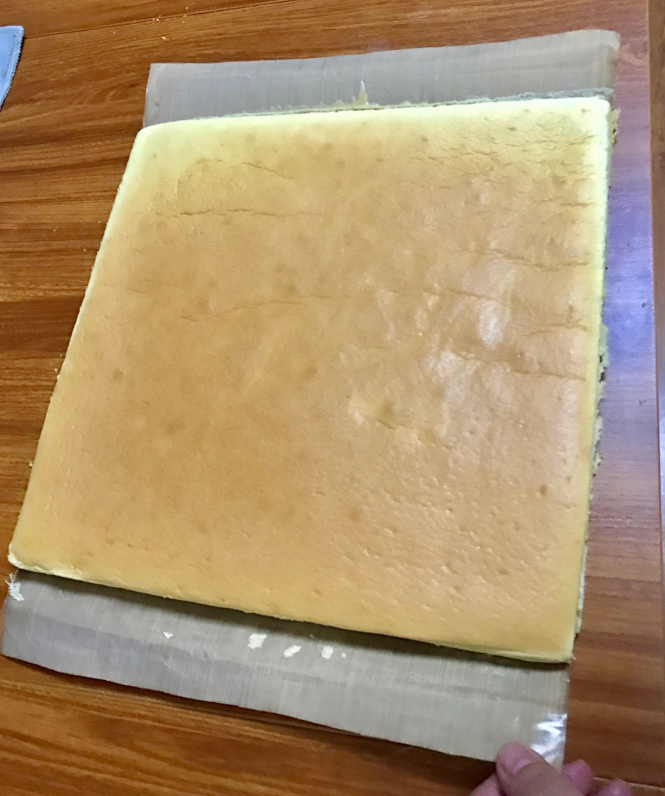 斑马纹蛋糕卷,取出后,震摔一下去掉热气,然后从烤盘拿出来。晾一分钟,然后表面放个物件,帮忙把蛋糕卷翻过来,趁热撕掉油纸